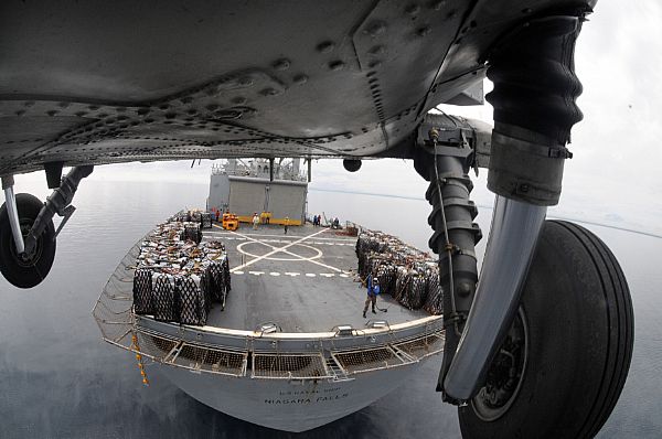 A HH-60H Seahawk helicopter from Helicopter Anti-Submarine Squadron (HS) 4 lifts another pallet of bottled water from the deck of Military Sealift Command combat stores ship USNS Niagara Falls (T-AFS 3) for delivery to Kalibo, Republic of the Philippines