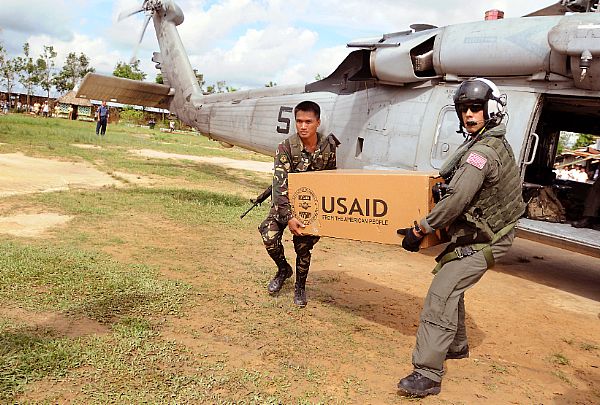 Aviation Warfare Systems Operator 2nd Class Anthony Chavez, a native of San Bernardino, Calif., works with a soldier from the Armed forces of the Philippines to move relief supplies to a school on the Panay Island.