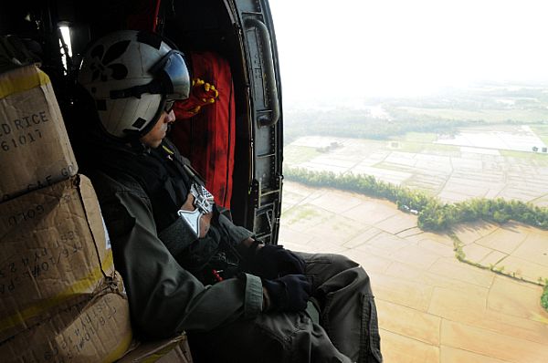 Aviation Warfare Systems Operator 2nd Class Anthony Chavez, of San Bernardino, Calif., looks over flooded areas in the Republic of the Philippines caused by Typhoon Fengshen. Riding in an SH-60F Seahawk assigned to the 