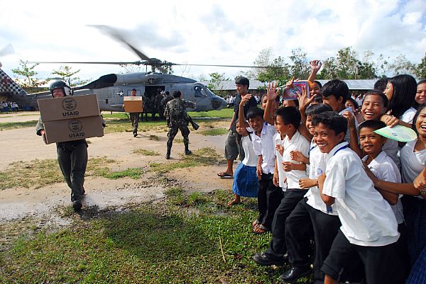 Aviation Warfare Systems Operator 2nd Class Jeremy Thomas, a native of Warren, Ohio, carries supplies to local citizens of Balasan, Philippines. Thomas is a helicopter crewman with the 