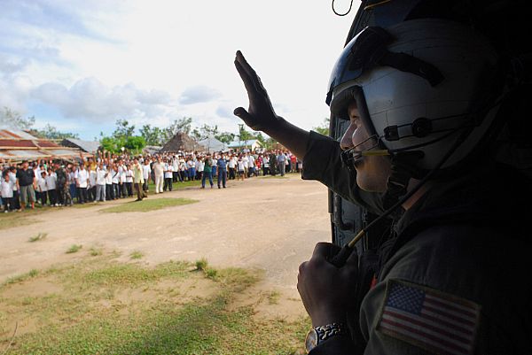 Aviation Warfare Systems Operator 2nd Class Jeremy Thomas, a native of Warren, Ohio, waves to citizens of the Municipality of Balasan, Philippines after delivering hygiene items, water and tents to the remote city. Thomas is a helicopter crewman with the 