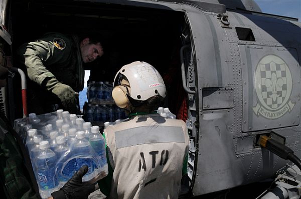 Chief Aviation Warfare Systems Operator Andrew Smith, of New Castle, Del., helps load water onto an SH-60F Seahawk
