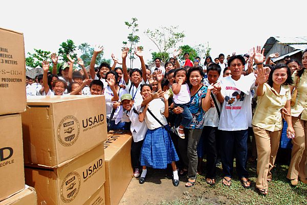 Citizens from the Municipality of Balasan, Philippines wave after receiving supplies from air crewmen assigned to the 