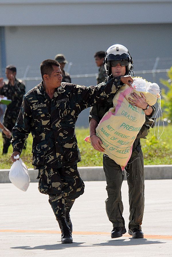 Lt. Brandon Sheets, right, carries a 100-pound sack of rice while a soldier from the Armed Forces of the Philippines lends a hand trying to keep the bag closed. The rice will be delivered to the remote location of Binglusan on the island of Panay.