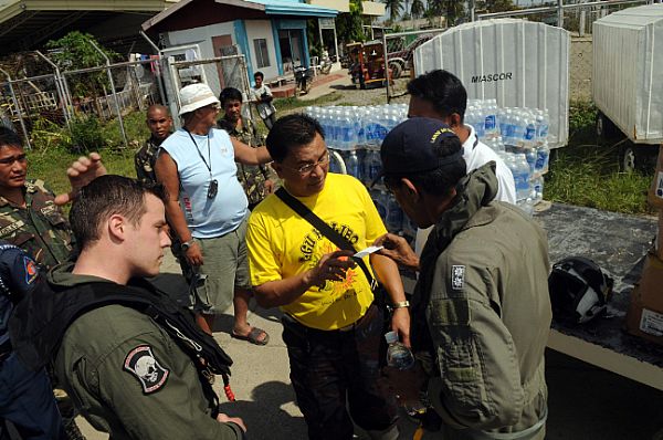 Raymar Rebaldo, mayor of Kalibo, center, receives food and water delivered from the Nimitz-class aircraft carrier USS Ronald Reagan (CVN 76) to be distributed throughout his town, an area in devastation after the effects of Typhoon Fengshen. Armed Forces of the Philippines (AFP), U.S. Navy personnel, and civilians worked together to unload the cargo.