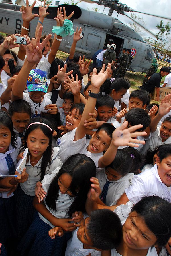 Residents from the Municipality of Balasan, Philippines wave and cheer after Sailors assigned to the 