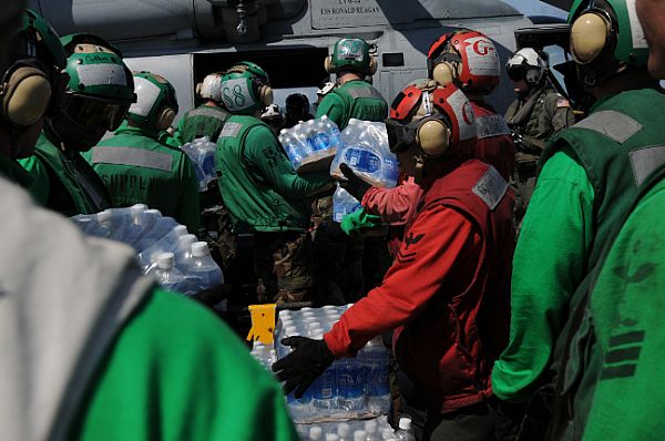 Sailors aboard the Nimitz-class aircraft carrier USS Ronald Reagan (CVN 76) load bottles of water onto an SH-60F Seahawk