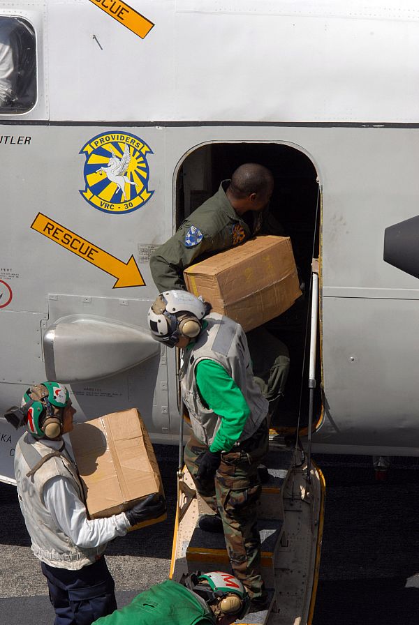 Sailors load cases of water bound for the Philippines onto a C-2A Greyhound