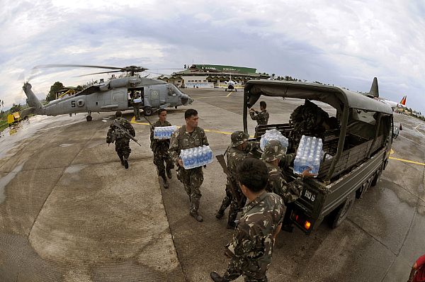 Servicemen from the United States Navy and the Philippine Army work together unloading much needed supplies