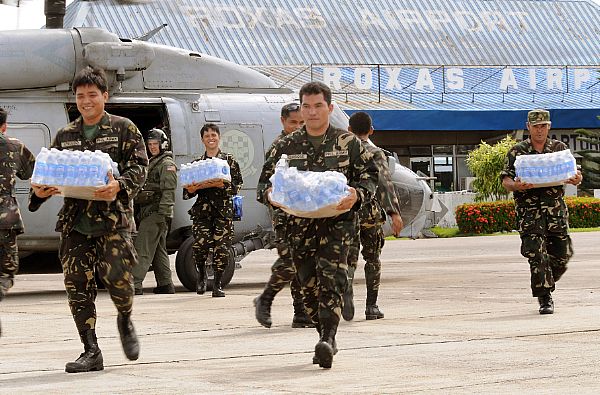 Servicemen of the Philippine Army transport bottled water from an SH-60 helicopter